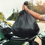 woman hand holding garbage black bag cleaning trash scaled