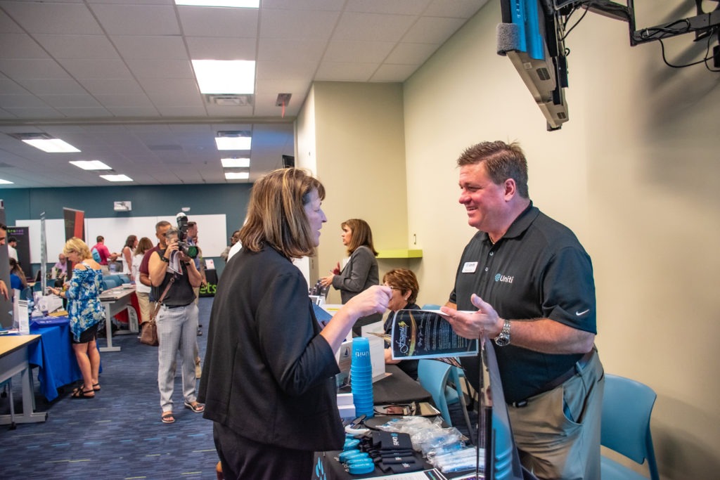 Business booth talks with attendee about their services