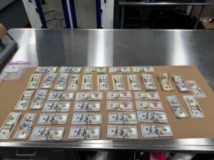 A variety of U S dollar bills are neatly arranged on a countertop The bills are placed in several rows and columns, including different denominations of $, $, $, and $ A small baggie is visible in the top left corner A variety of U S dollar bills are neatly arranged on a countertop The bills are placed in several rows and columns, including different denominations of $, $, $, and $ A small baggie is visible in the top left corner