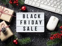 A lightbox with "Black Friday Sale" text is surrounded by a computer keyboard, a white mouse, wrapped gifts, red ornaments, and pine branches on a dark, speckled surface
