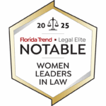 Hexagonal badge with a gold border showing the text “ Florida Trend Legal Elite Notable Women Leaders in Law,” along with a scale of justice icon at the top