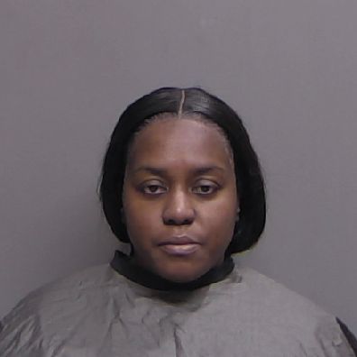 A woman with straight, shoulder length dark hair poses against a plain gray background, wearing a gray protective covering She has a neutral facial expression A woman with straight, shoulder length dark hair poses against a plain gray background, wearing a gray protective covering She has a neutral facial expression