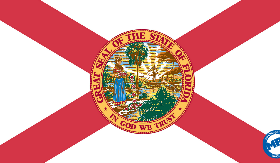 The flag of Florida features a red diagonal cross on a white background with the state seal in the center, showing a Seminole woman, water, a steamboat, and palm trees "In God We Trust" is written on the seal