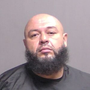A man with a bald head and a thick black beard is facing the camera against a plain gray background, wearing a dark shirt A man with a bald head and a thick black beard is facing the camera against a plain gray background, wearing a dark shirt