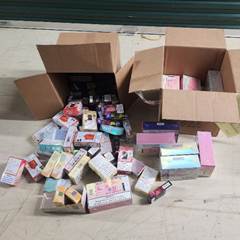 Two open cardboard boxes with many assorted cosmetic or skincare product boxes scattered on the floor in front of them The background includes a green shutter and a light colored floor Two open cardboard boxes with many assorted cosmetic or skincare product boxes scattered on the floor in front of them The background includes a green shutter and a light colored floor