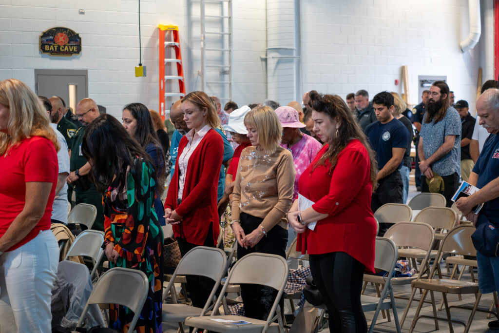 A group of people standing in a building with heads bowed in prayer or reflection A group of people standing in a building with heads bowed in prayer or reflection